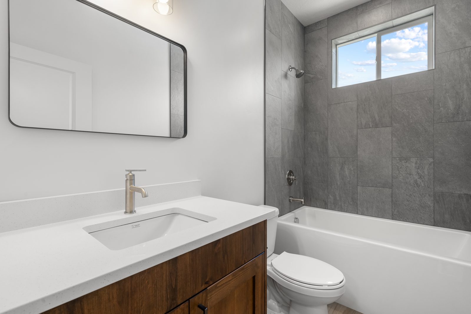 Bath with gray tile surround and custom vanity
